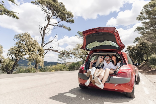 Bezpłatne zdjęcie przyjaciele robią przyjemność w bagażniku samochodu na drodze