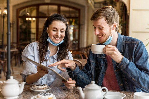 Przyjaciele rozmawiający w restauracji, mając maski medyczne na brodzie