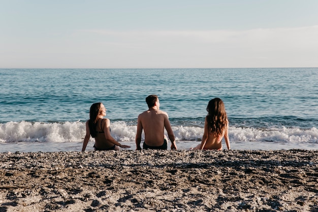 Bezpłatne zdjęcie przyjaciele siedzi na plaży