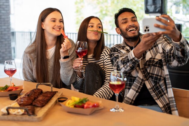 Przyjaciele śmiejący się podczas robienia selfie na przyjęciu w restauracji