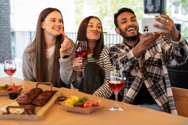 Przyjaciele śmiejący się podczas robienia selfie na przyjęciu w restauracji