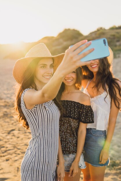 Przyjaciele stwarzające dla selfie na plaży