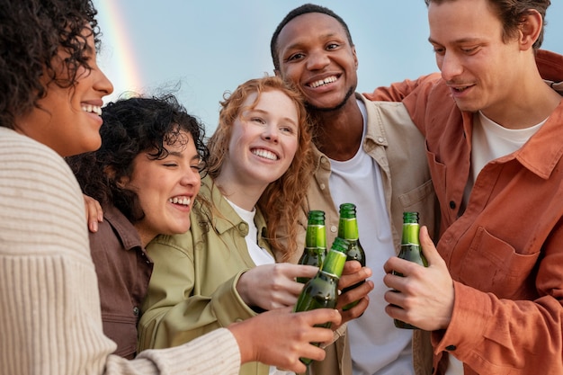 Bezpłatne zdjęcie przyjaciele uśmiechający się i pijący piwo podczas imprezy plenerowej