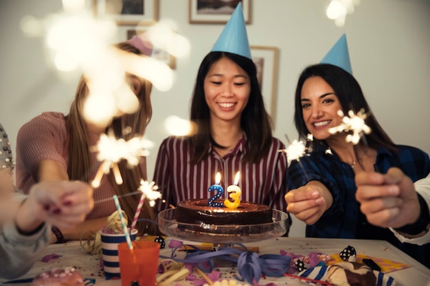 Przyjaciele z tortem i sparklers na przyjęciu urodzinowym