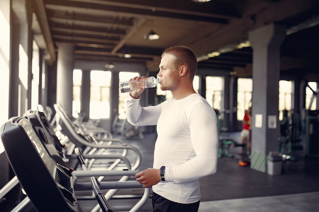 Przystojna mężczyzna woda pitna na karuzeli w gym