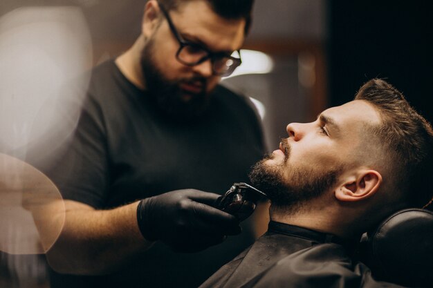 Przystojnego mężczyzna tnąca broda przy fryzjera męskiego sklepu salonem