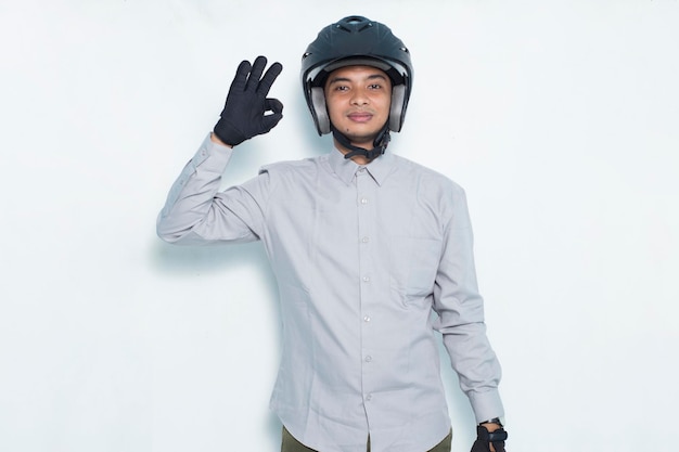Przystojny azjatycki mężczyzna w kasku motocyklowym pokazujący kciuk w górę ok gest na białym tle