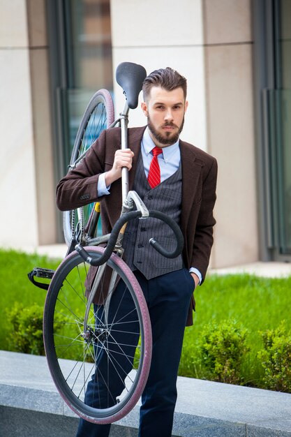 Przystojny biznesmen niosący swój rower