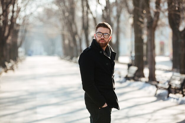 Przystojny brodaty młody człowiek stoi outdoors w zimie