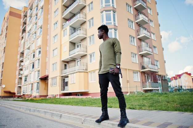 Przystojny i atrakcyjny afroamerykanin pozuje obok wysokiego budynku na ulicy