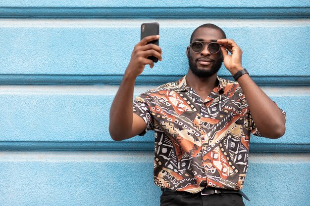 Przystojny mężczyzna biorący selfie z nowoczesnym smartfonem na zewnątrz