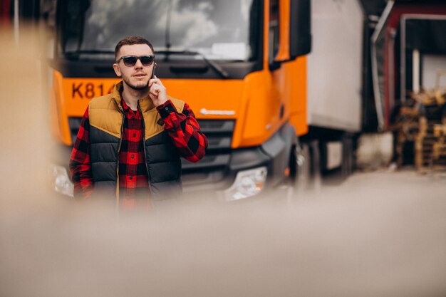 Przystojny mężczyzna kierowca ciężarówki stojący przy ciężarówce