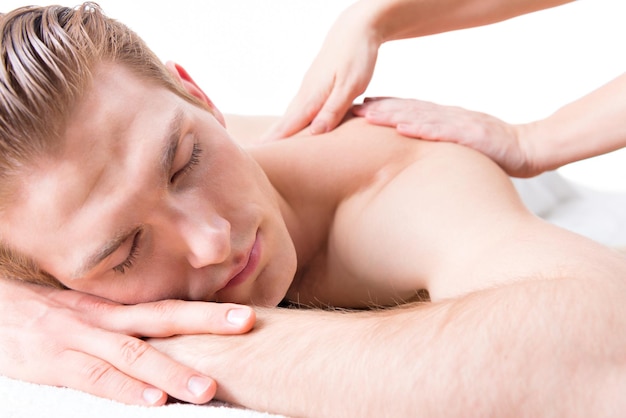 Przystojny mężczyzna leżący w salonie spa korzystający z głębokiego masażu tkanek pleców.