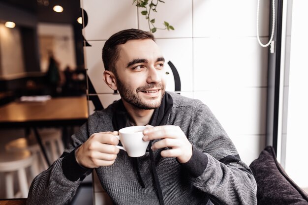 Przystojny mężczyzna pije filiżankę kawy w kawiarni