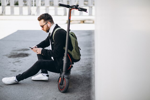 Przystojny mężczyzna robi zakupy online na telefonie na hulajnoga