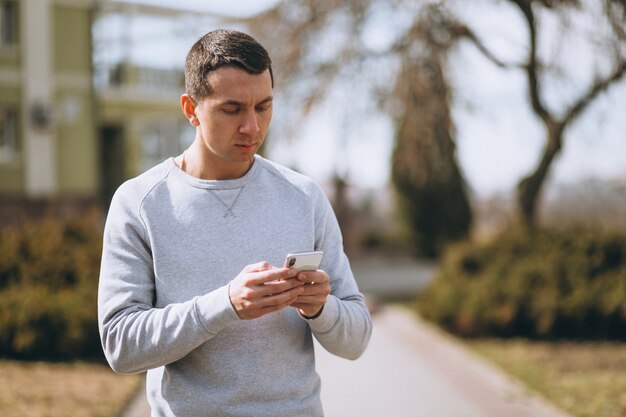 Przystojny mężczyzna rozmawia przez telefon na zewnątrz w parku