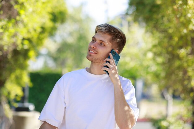Przystojny mężczyzna rozmawia przez telefon podczas spaceru po parku Wysokiej jakości zdjęcie