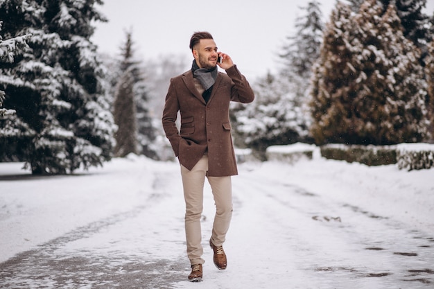 Przystojny mężczyzna rozmawia przez telefon w winter park