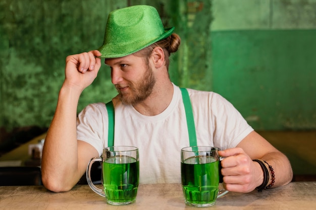 Bezpłatne zdjęcie przystojny mężczyzna świętuje ul. patrick's day z napojami