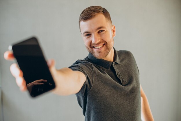 Przystojny mężczyzna trzymający telefon komórkowy i pokazujący go w aparacie