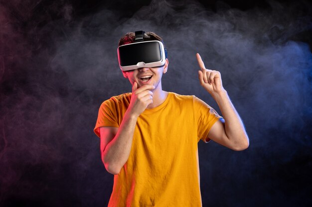 Przystojny mężczyzna ubrany w zestaw słuchawkowy wirtualnej rzeczywistości na ciemnej powierzchni