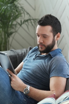 Przystojny młody mężczyzna za pomocą cyfrowego tabletu lub ebooka