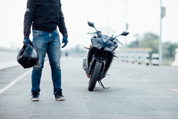Przystojny motorbiker z hełmem w rękach motocykl