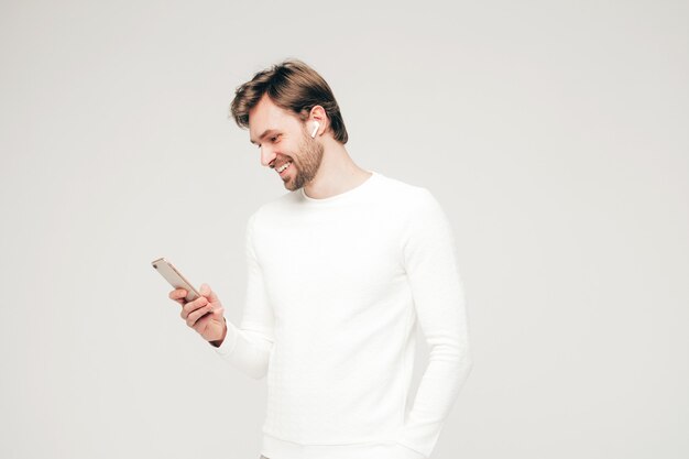 Przystojny uśmiechnięty hipster drwal seksualny model biznesmena ubrany w biały swobodny sweter i spodnie