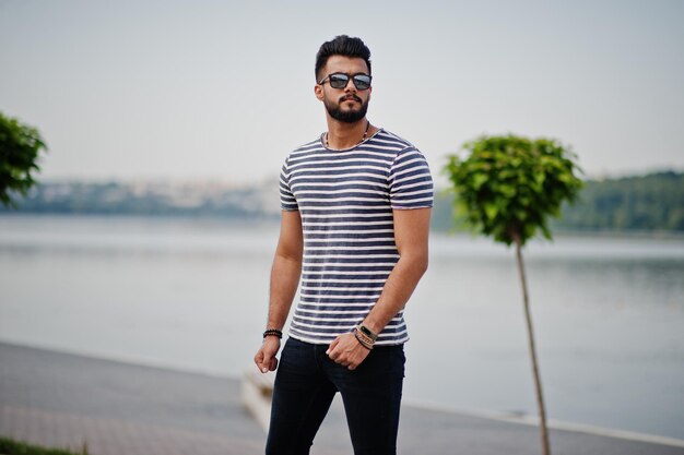 Przystojny wysoki arabski model brody mężczyzny w koszuli w paski pozował na zewnątrz Modny arabski facet w okularach przeciwsłonecznych