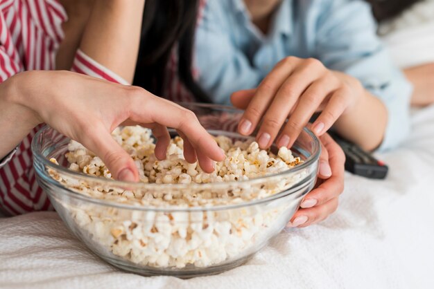 Przytnij ręce kobiet jedzących popcorn