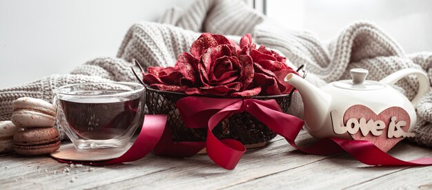 Przytulna, domowa kompozycja miłości na Walentynki z elementami dekoracyjnymi i kwiatami.