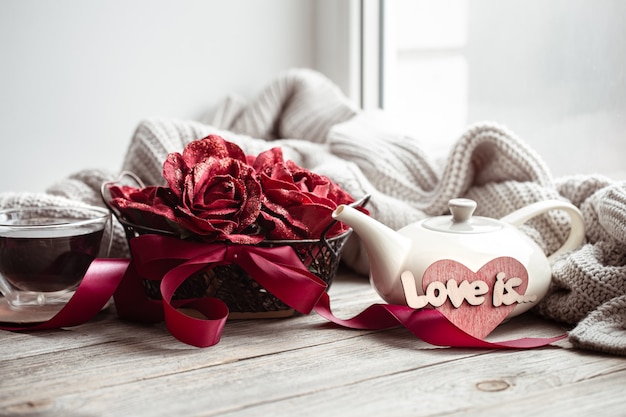 Przytulna, domowa kompozycja miłości na Walentynki z elementami dekoracyjnymi i kwiatami.