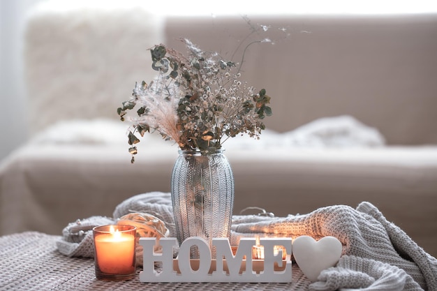 Przytulna kompozycja z dekoracyjnymi świecami słownymi home i wazonem z suszonymi kwiatami