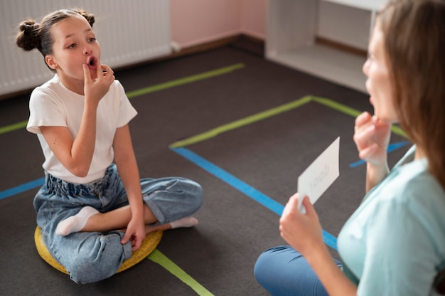 Bezpłatne zdjęcie psycholog pomaga małej dziewczynce w terapii mowy w pomieszczeniu