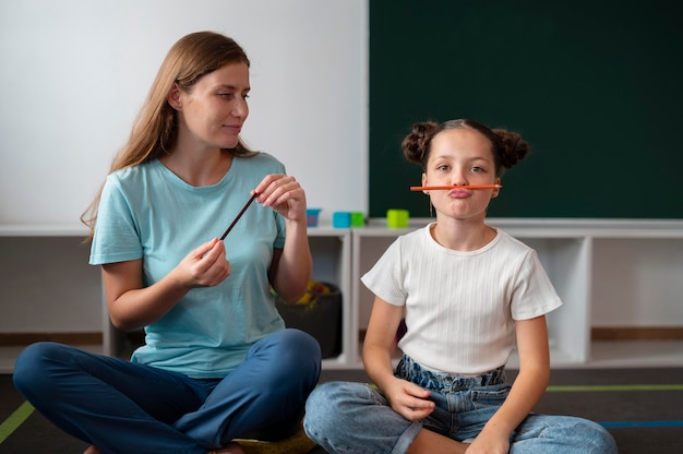 Psycholog pomaga małej dziewczynce w terapii mowy w pomieszczeniu