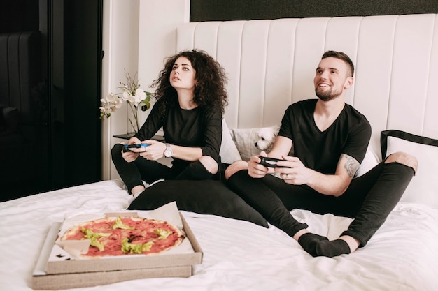 Pudełko Z Pizzą Stoi Przed Mężczyzną I Kobietą Grającą Na Ps Na łóżku