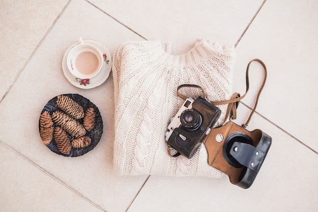 Bezpłatne zdjęcie pulower i aparat fotograficzny położony w pobliżu kawy i pinecones