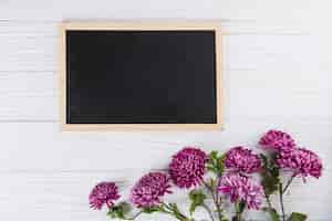 Bezpłatne zdjęcie purpura kwitnie z pustym chalkboard na bielu stole