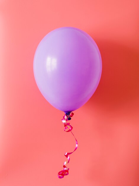 Purpurowy balon na różowym tle