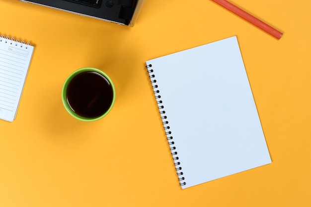 Pusta strona notatnika, laptop, filiżanka kawy i ołówek. pusta podkładka do pisania pomysłów i inspiracji na kolorowym tle