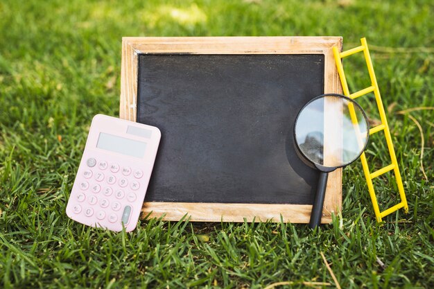 Pusta tablica z kalkulatorem i lupą na trawie