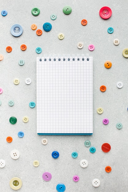 Bezpłatne zdjęcie pusty notatnik otoczony kolorowymi guzikami