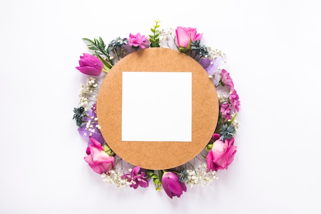Bezpłatne zdjęcie pusty papier na różnych kwiatach na bielu stole