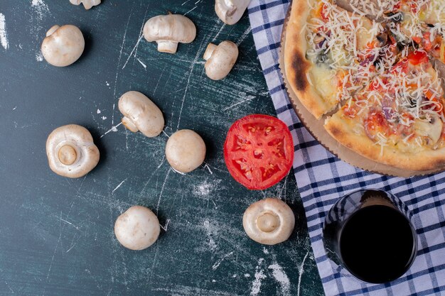 Pyszna pizza grzybowa z szklanką soku i świeżymi warzywami na marmurze.