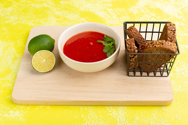 Bezpłatne zdjęcie pyszna zupa pomidorowa z bochenkami chleba i plasterkiem cytryny na żółto, zupa obiadowa warzywna