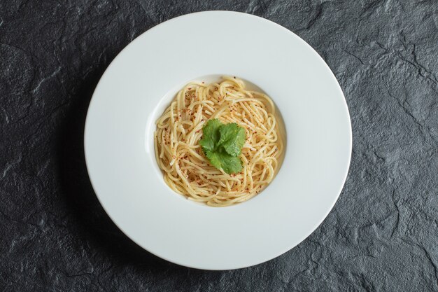 Pyszne spaghetti z zielenią na białym talerzu.