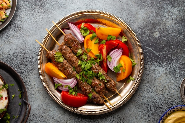 Pyszny kebab mięsny z sałatką ze świeżych warzyw podawany na rustykalnym talerzu, tradycyjne bliskowschodnie danie. smaczny i zdrowy posiłek kuchni arabskiej lub śródziemnomorskiej z góry