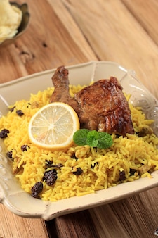 Pyszny pikantny kurczak biryani w brązowym talerzu drewniane tło, indyjskie lub pakistańskie jedzenie ramzan. tradycyjne pikantne indyjskie jedzenie, posiłek iftar, kolacja ramadanowa.