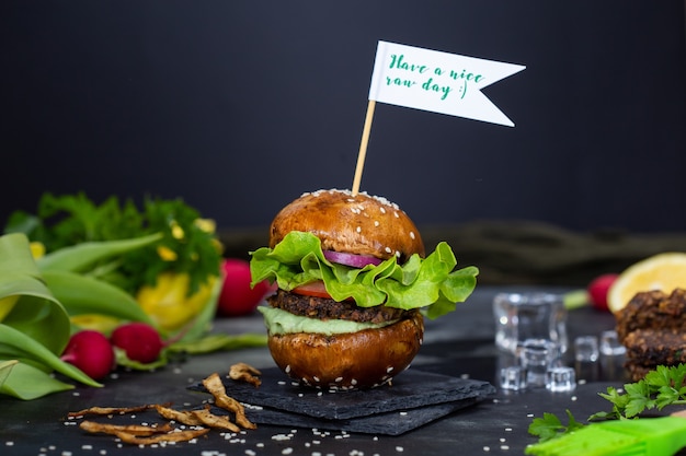 Bezpłatne zdjęcie pyszny wegański hamburger z napisem „have a nice raw day” na patyku