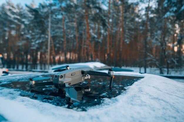 Quadrocopter stojący na dachu zaśnieżonego samochodu